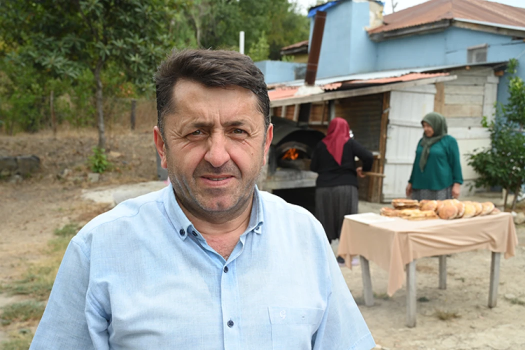İmam taş fırında pişirdiği ekmekleri köylülere ikram ediyor