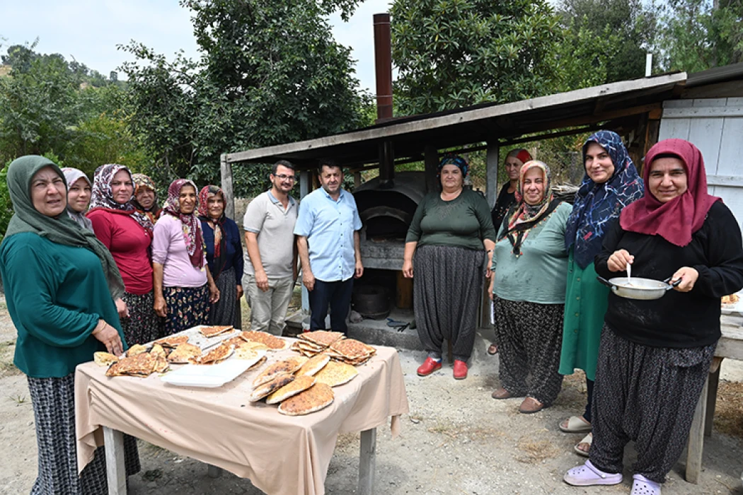İmam taş fırında pişirdiği ekmekleri köylülere ikram ediyor