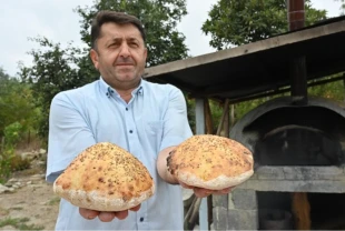 İmam taş fırında pişirdiği ekmekleri köylülere ikram ediyor
