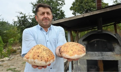 İmam taş fırında pişirdiği ekmekleri köylülere ikram ediyor