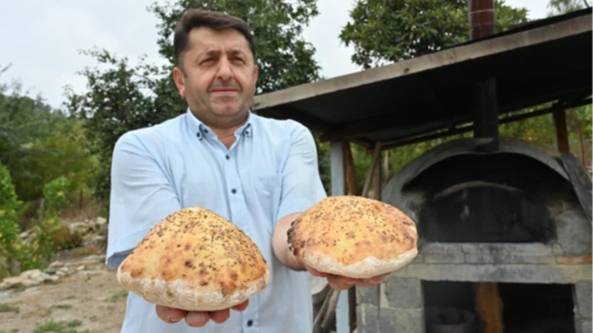 İmam taş fırında pişirdiği ekmekleri köylülere ikram ediyor