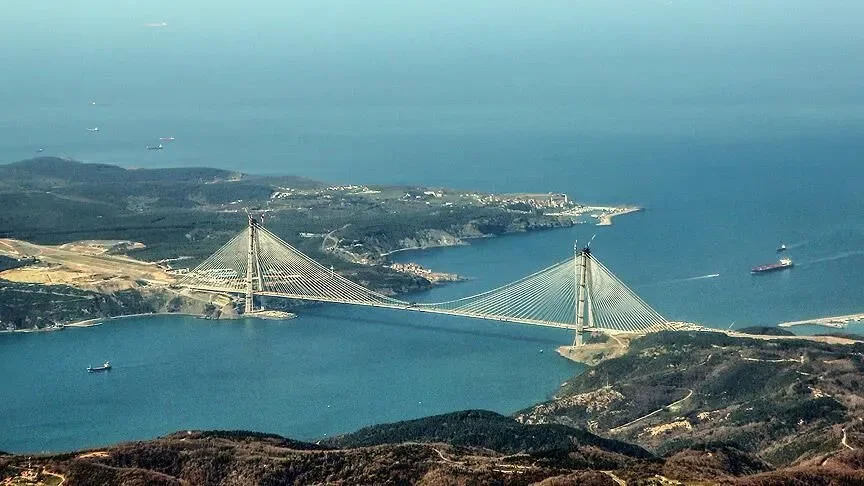 YAVUZ SULTAN SELİM KÖPRÜSÜ: BOĞAZIN KUZEYİNDE LOJİSTİK HAT İstanbul Boğazı'nın kuzeyinde inşa edilen Yavuz Sultan Selim Köprüsü, Kuzey Marmara Otoyolu'nun en önemli parçalarından biri olarak Türkiye'nin doğu-batı ulaşım koridorunda görev yapıyor. Köprü 1.408 metrelik ana açıklığa , yaklaşık 322 metre yüksekliğindeki kulelere ve yaklaşık 59 metrelik tabliye genişliğine sahip. Yapı, karayolunun yanı sıra demiryolu geçişine uygun tasarımıyla da diğer Boğaz köprülerinden ayrılıyor. Özellikle ağır vasıta ve transit trafiğin İstanbul'un kuzeyinden yönlendirilmesinde önemli bir alternatif oluşturan köprü, Asya ile Avrupa arasındaki karayolu lojistiğinin kritik geçiş noktalarından biri.